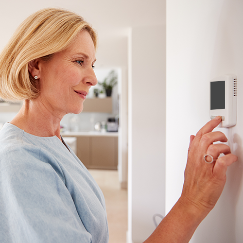 Woman adjusting thermostat in home