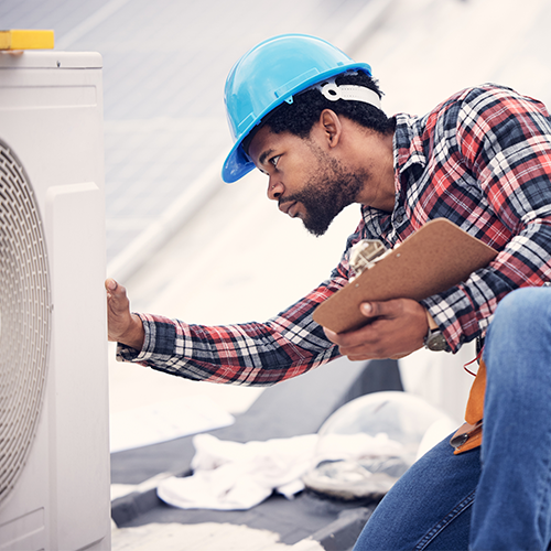 Man with clipboard looking at air conditioning unit