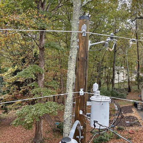 A power pole, wires, transformer and trees